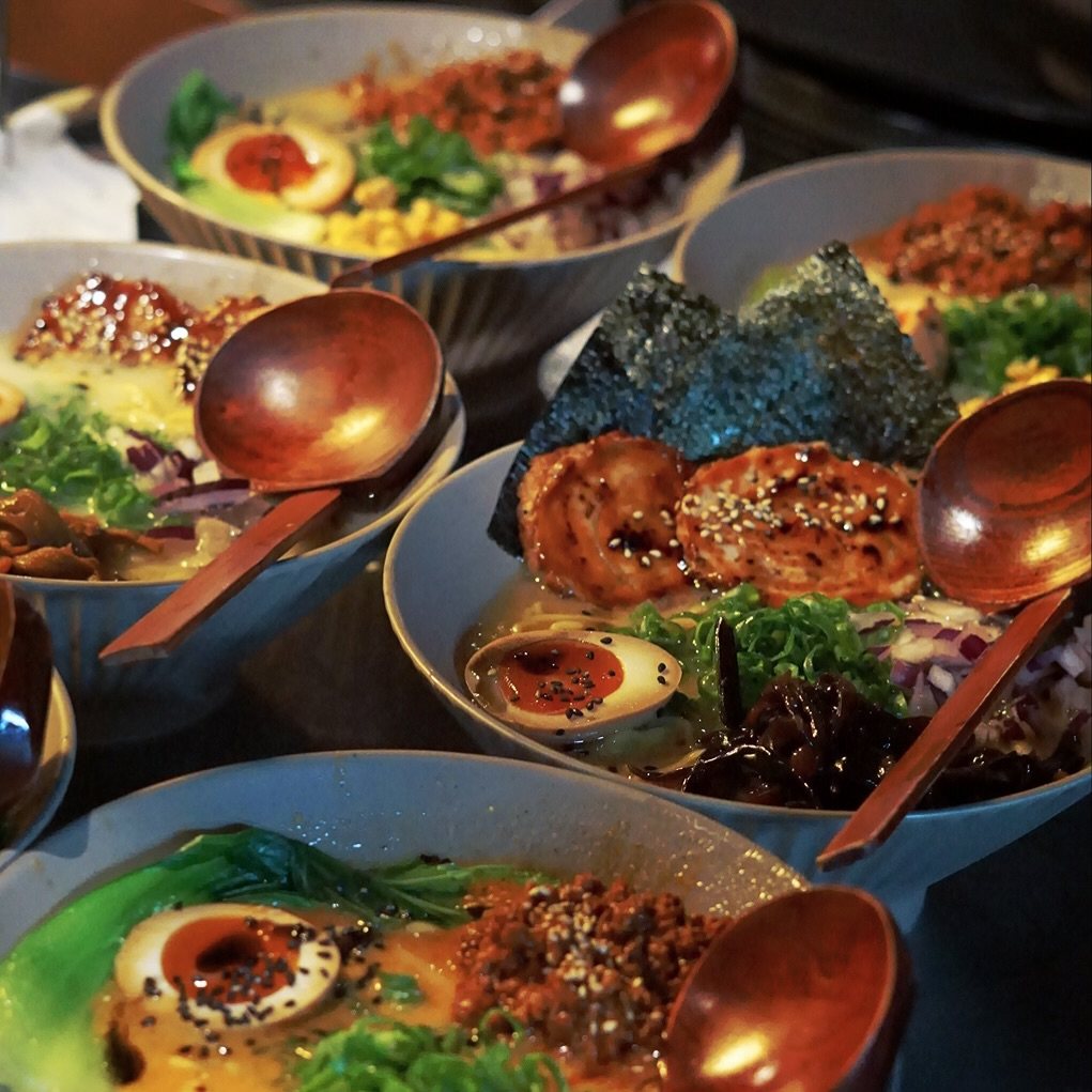 Mehrere Schalen Ramen mit Holzlöffeln im DAIKAN